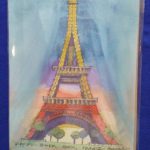 Image Description:[The background is a royal blue tablecloth with a painting made by Tom Posedly of the Eiffel Tower, Paris, France. The background is light blue in the sky with a green and brown ground, and green leafed trees with brown trunks. The Eiffel Tower has hints of purple, red, and yellow behind it. At the bottom, the words “EIFFEL TOWER, PARIS, FRANCE POSEDLY” are under the painting of the Eiffel Tower in black. The Eiffel Tower is wrought-iron lattice tower in structure. It is painted yellow at the first and second levels while the third is red.]